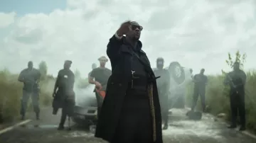 Le manteau long avec une sorte de petite cape doublée à l'arrière qui s'arrête au niveau du dos de SDM dans son clip Gâchette