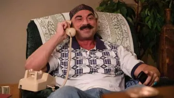 Polo imprimé porté par le Cheikh de fer (Brett Azar) comme on le voit dans les tenues de la série télévisée Young Rock (saison 3 épisode 11)