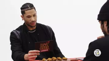 Chaqueta negra Varsity usada por Josh Hart como se ve en Hot Ones