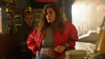 The orange-red bomber jacket worn by Nora Kader (Manon Azem) in the series Mercato (Season 1 Episode 1)