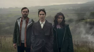 Manteau de pluie vert à fermeture éclair porté par Emmy (Robyn Cara) dans les tenues de la série télévisée Bodkin (saison 1)