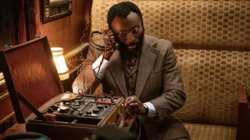 Anteojos redondos usados por M. Heron (Babs Olusanmokun) como se ve en El Ministerio de Guerra Poco Caballerosa