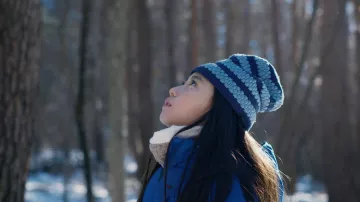 Bonnet bleu en tricot rayé porté par Hana (Ryo Nishikawa) comme on le voit dans les tenues du film Le mal n’existe pas