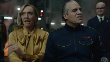 Mickey 17 Movie Wardrobe: Toni Collette is wearing Necktie Blouse in mustard yellow to portray Gwen Johansen