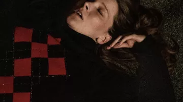 Pull à carreaux scintillants noir et rouge porté par Maud (Morfydd Clark) à Saint Maud