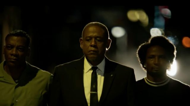 The black t-shirt with white collar of Nat Pettigrew (Elvis Nolasco) in the series Godfather of Harlem (S01E02)
